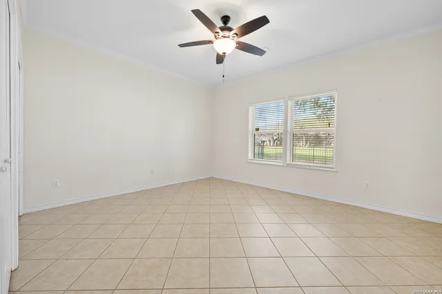 an empty room with windows and ceiling fan