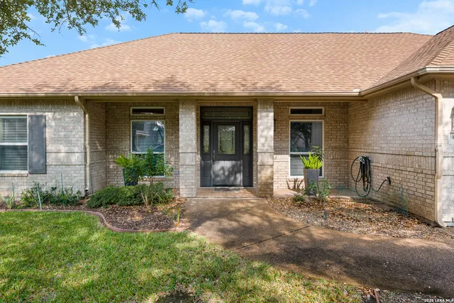 a view of a house with brick walls and a yard with plants