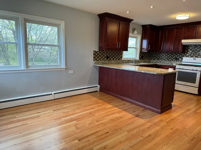 a kitchen with stainless steel appliances granite countertop a stove and a wooden cabinets