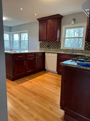 a kitchen with stainless steel appliances granite countertop wooden cabinets a stove a sink and a window