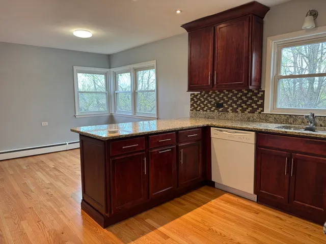 a kitchen with granite countertop a sink cabinets and wooden floor