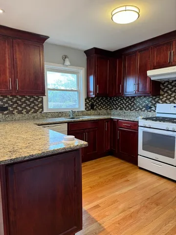 a kitchen with stainless steel appliances granite countertop wooden cabinets a oven and granite counter tops