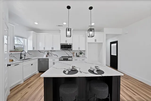 a kitchen with stainless steel appliances stove refrigerator dining table and chairs