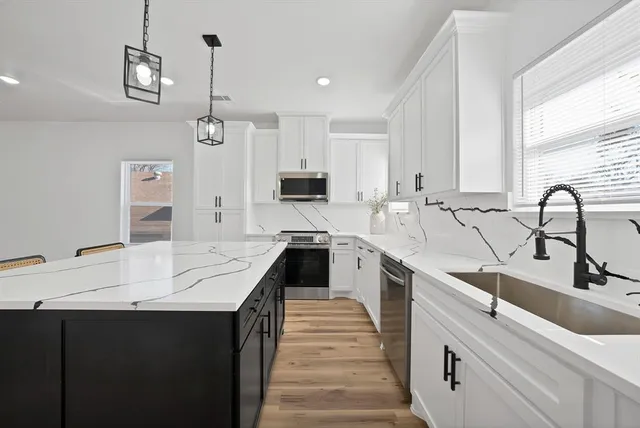 a kitchen with kitchen island granite countertop a sink stove and cabinets