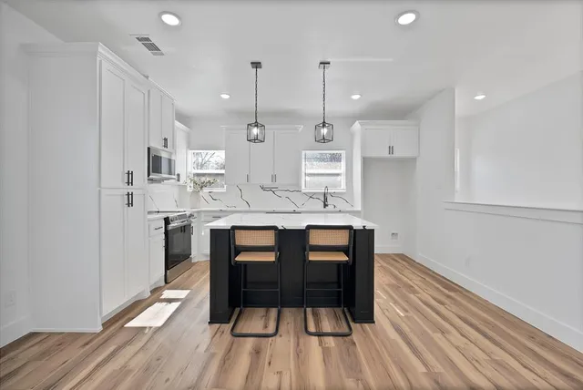 a kitchen with kitchen island white cabinets and stainless steel appliances