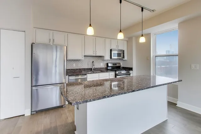 a kitchen with stainless steel appliances granite countertop a refrigerator a stove a sink and a refrigerator