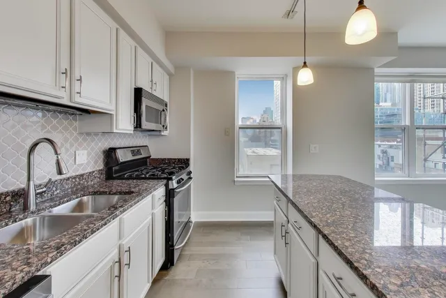 a kitchen with granite countertop a sink a stove and cabinets