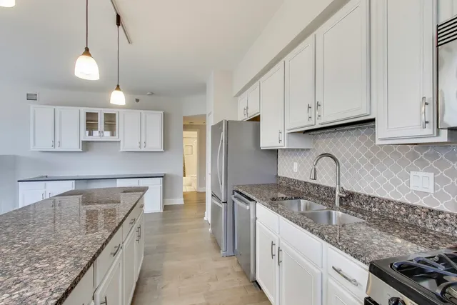 a kitchen with granite countertop a sink a counter space stainless steel appliances and cabinets