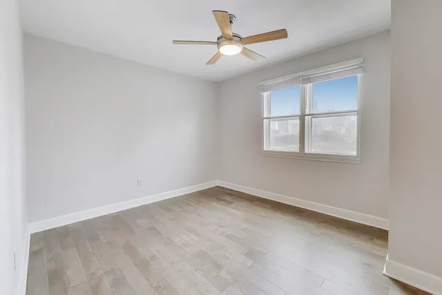 an empty room with windows and fan