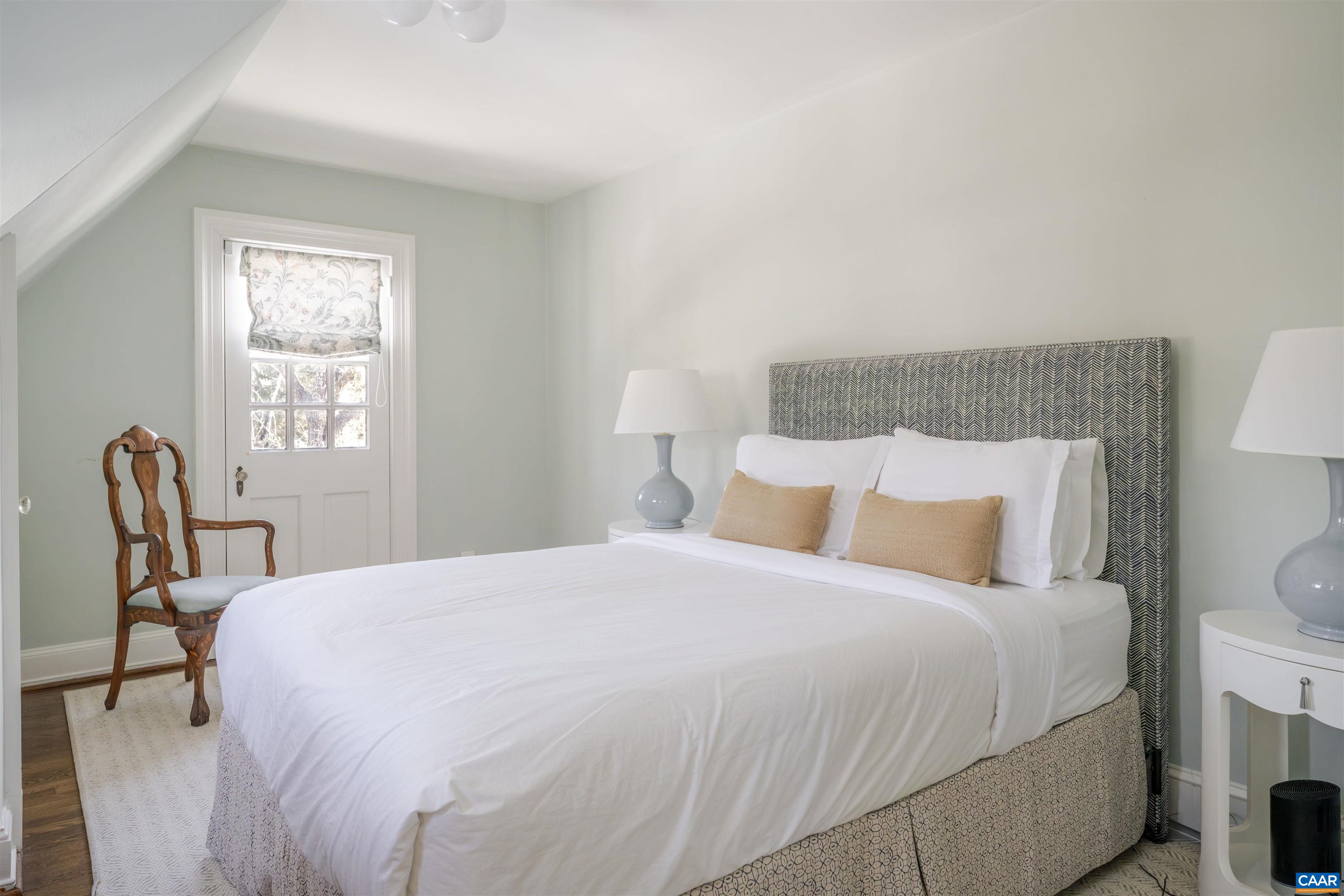 921 Rugby Road Charlottesville, VA 22903 - Photo 32 of 41 a large bed sitting in a bedroom next to a window with chair and lamp