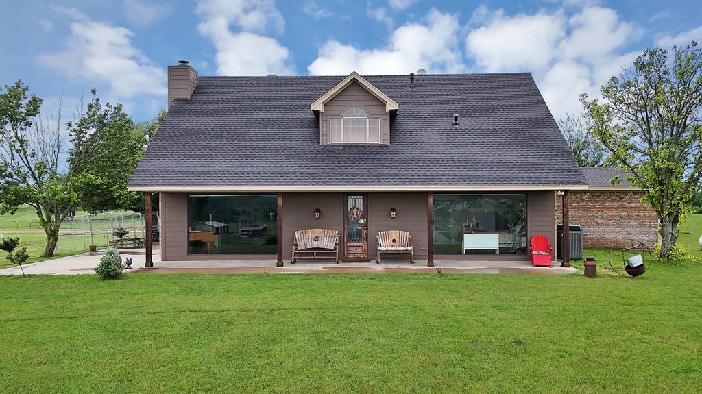 Exterior featuring a dark shingle roof, chimney, dormer with arched window, and a covered porch