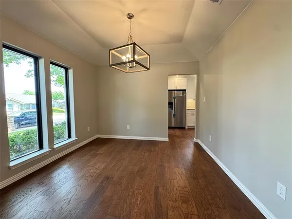 a view of empty room with wooden floor and window