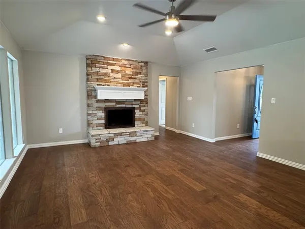 an empty room with windows fireplace and wooden floor