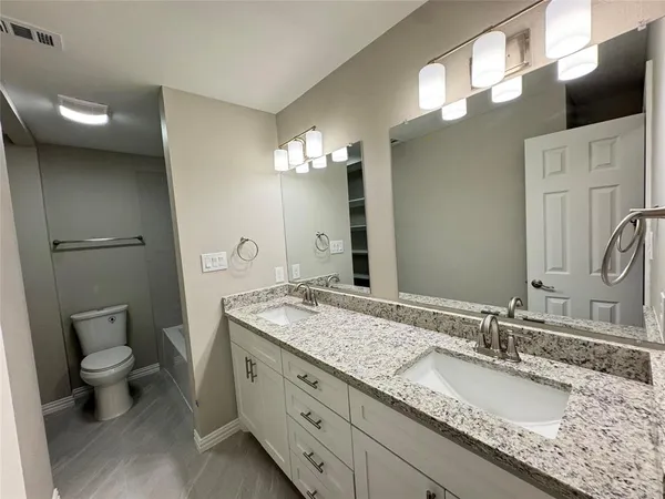 a bathroom with a granite countertop sink a toilet and a large mirror