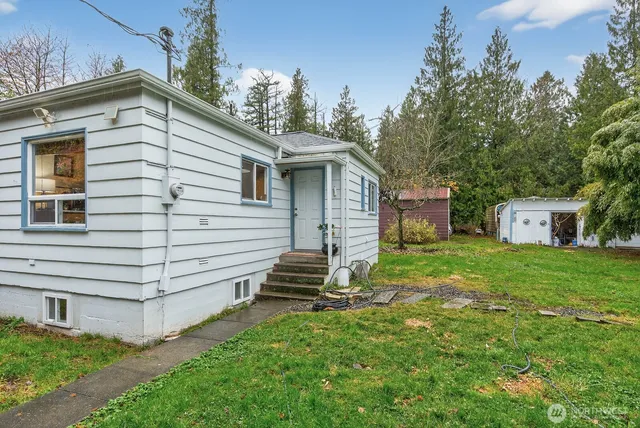 a front view of house with yard and trees in the background