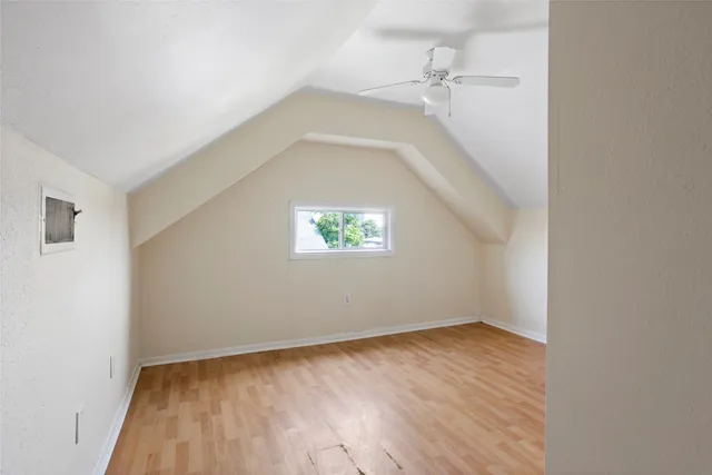 an empty room with wooden floor cabinet and windows