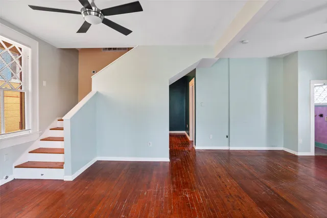 a view of an empty room with wooden floor and stairs