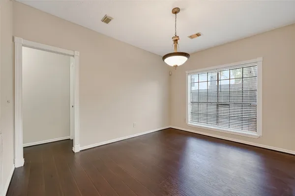an empty room with wooden floor chandelier fan and windows