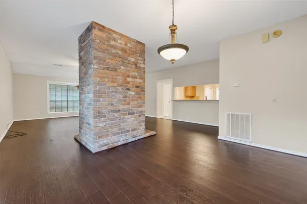 an empty room with wooden floor chandelier and windows