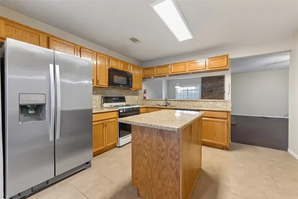 a kitchen with stainless steel appliances granite countertop a refrigerator a stove and a sink with large window