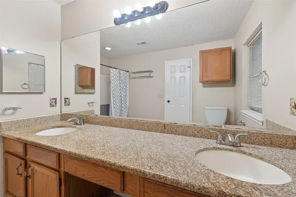 a bathroom with a granite countertop double vanity sink and mirror