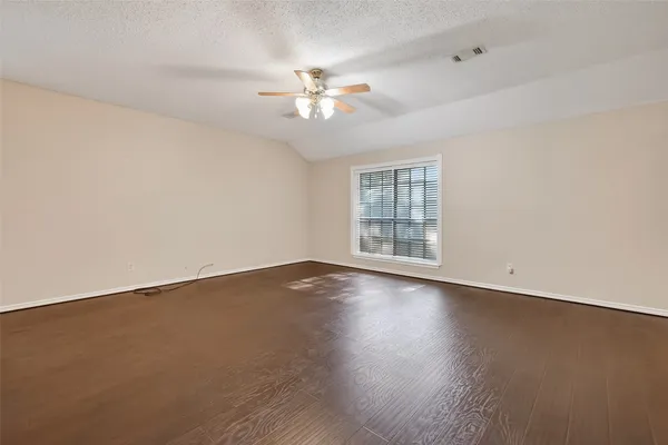 an empty room with wooden floor fan and windows
