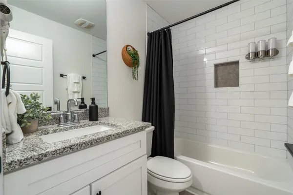 a bathroom with a granite countertop sink mirror vanity and toilet