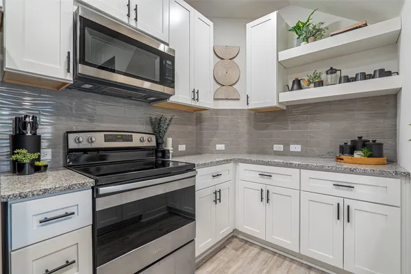 a kitchen with granite countertop cabinets stainless steel appliances and wooden floor