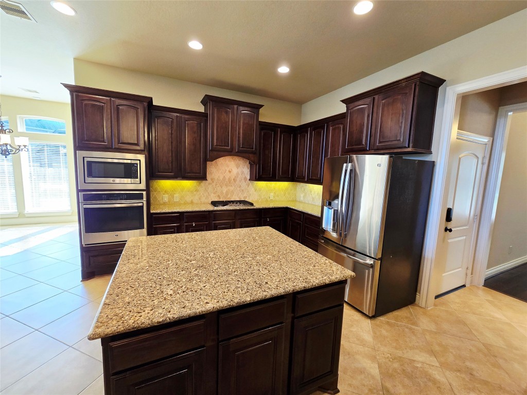 4311 Piper Shadow Lane Katy, TX 77494 - Photo 19 of 29 a kitchen with kitchen island granite countertop wooden cabinets refrigerator and stove