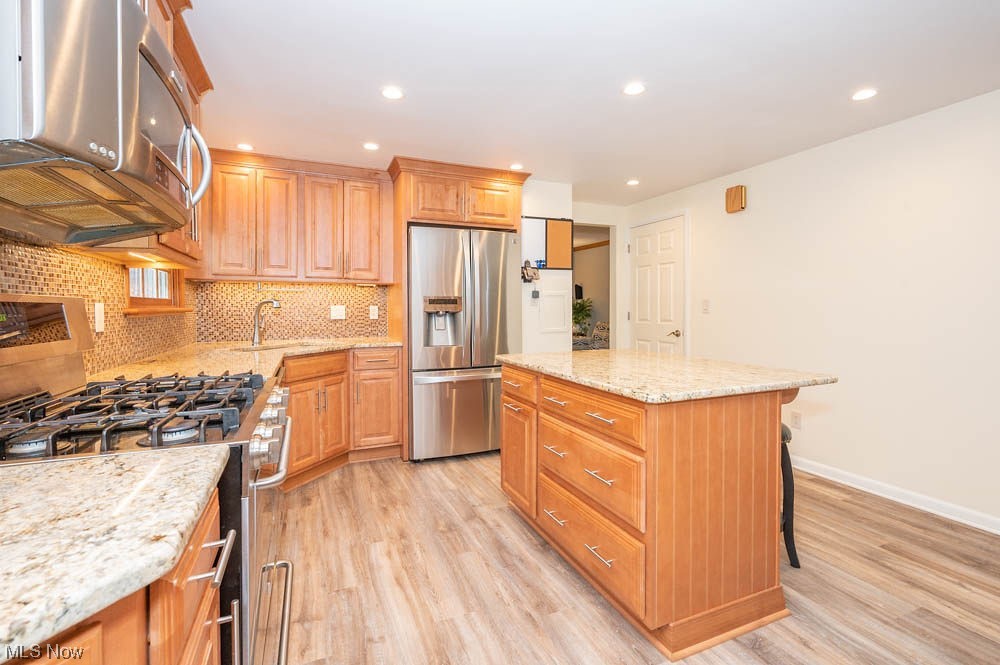 4639 Tippecanoe Road Youngstown, OH 44511 - Photo 7 of 36 Kitchen with light stone counters, tasteful backsplash, stainless steel fridge with ice dispenser, light hardwood / wood-style floors, and a center island