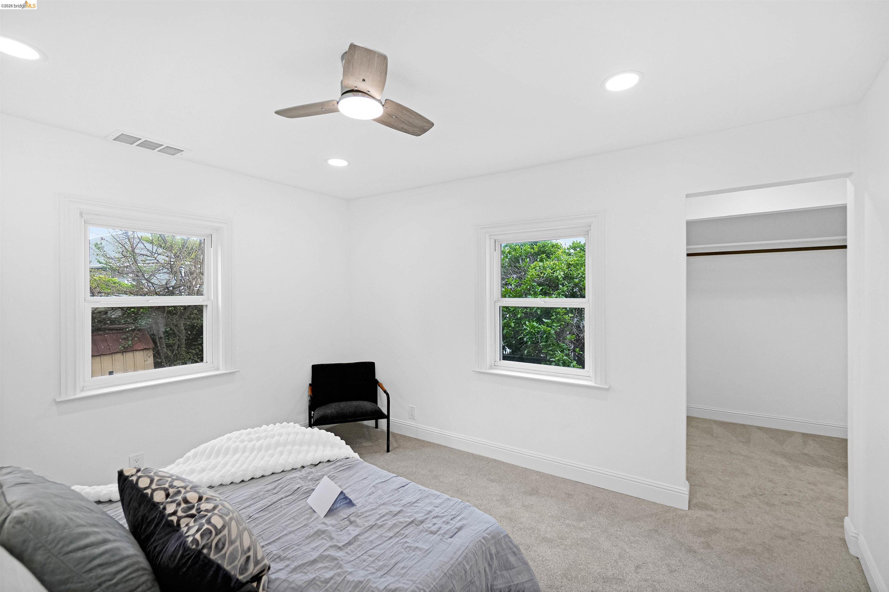 1812 Woolsey Street Berkeley, CA 94703 - Photo 17 of 48 Room featuring light gray carpeting, two double-hung windows with white trim, and a contemporary ceiling fan with integrated lighting
