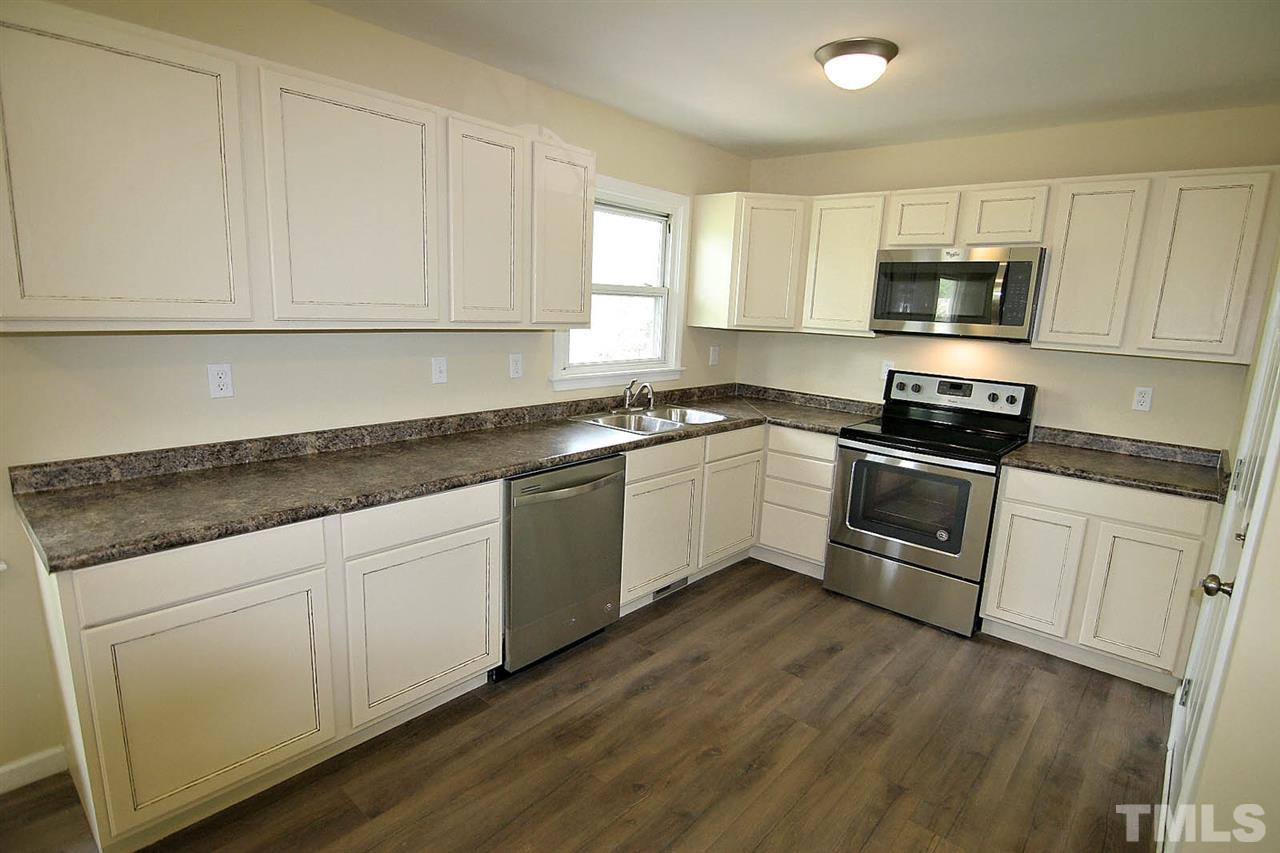 7033 Buck Road Wendell, NC 27591 - Photo 8 of 25 a kitchen with granite countertop white cabinets and stainless steel appliances