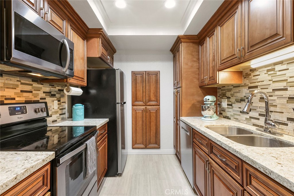20702 El Toro Road, Unit 226 Lake Forest, CA 92630 - Photo 9 of 39 a kitchen with stainless steel appliances granite countertop a sink a stove a refrigerator and a microwave oven with wooden floor