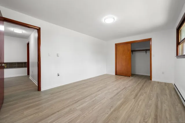a view of an empty room with wooden floor and closet