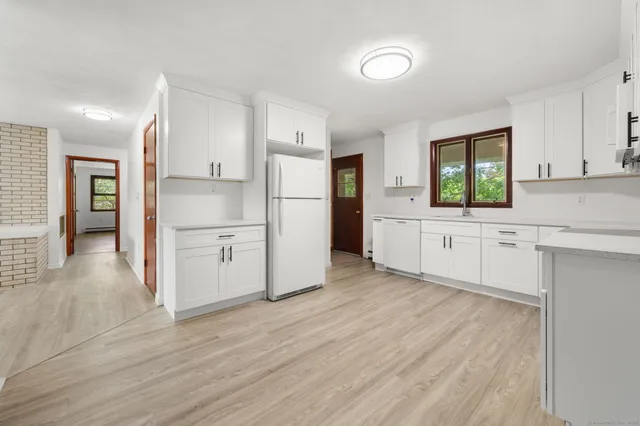 a kitchen with white cabinets and wooden floor