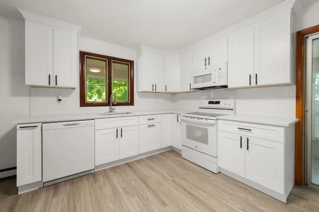 a kitchen with white cabinets white stainless steel appliances and sink