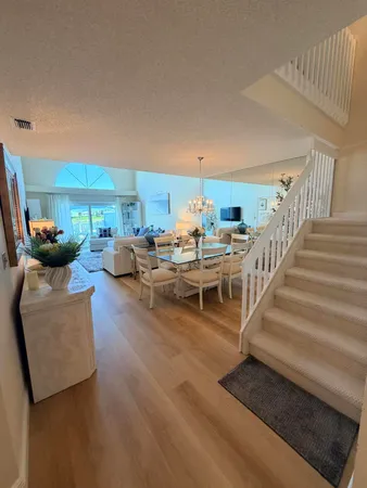 a living room with couches and kitchen view with wooden floor