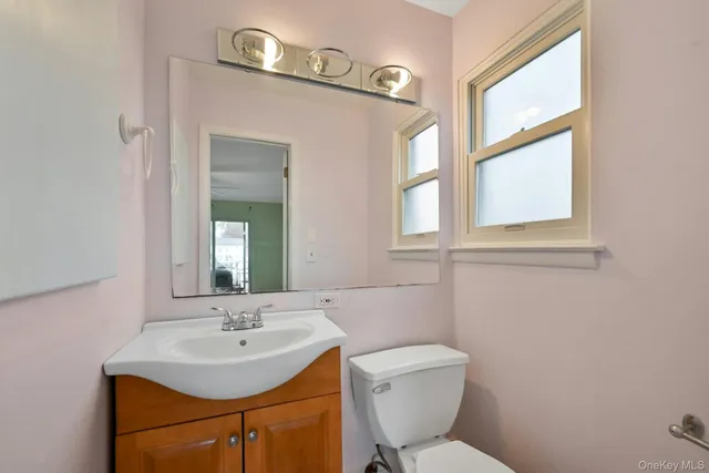 a bathroom with a toilet a sink a mirror and a window