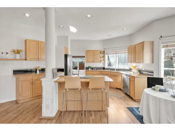 a living room with stainless steel appliances kitchen island granite countertop furniture and a wooden floor
