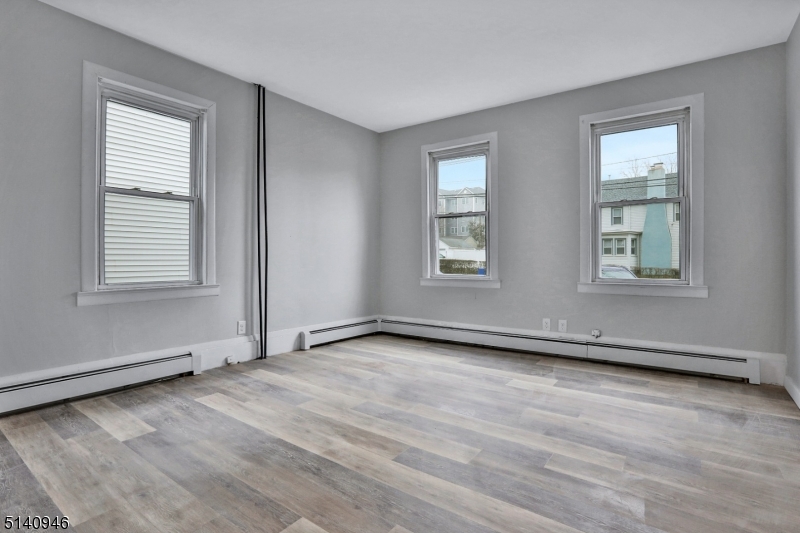 25 Kiel Avenue, Unit 1 Butler, NJ 07405 - Photo 11 of 13 an empty room with wooden floor and windows