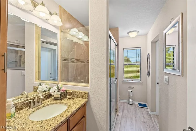 a bathroom with a granite countertop sink a mirror and a shower