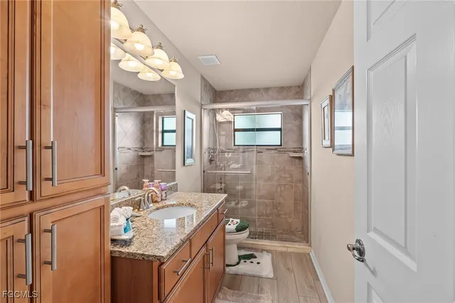 a bathroom with a granite countertop sink a mirror and a shower