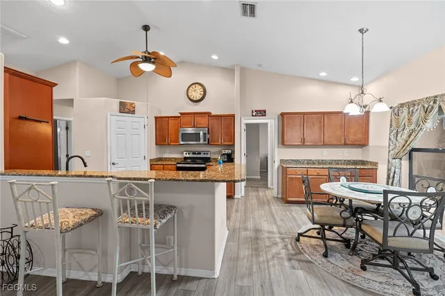 a kitchen with stainless steel appliances kitchen island granite countertop a stove a sink a dining table and chairs with wooden floor