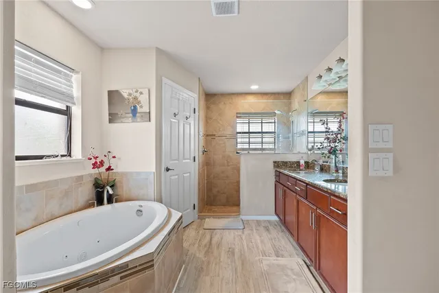 a bathroom with a granite countertop tub a sink and a large mirror