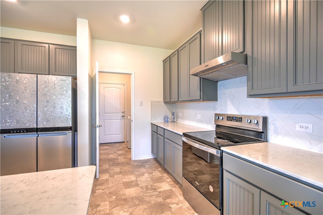 119 Lucky Texan Cove Jarrell, TX 76537 - Photo 15 of 33 a kitchen with kitchen island granite countertop a stove a sink and a refrigerator