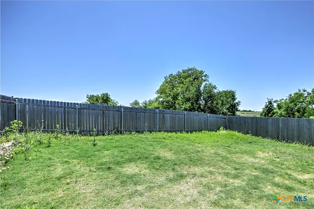 a view of a backyard with a fence and plants