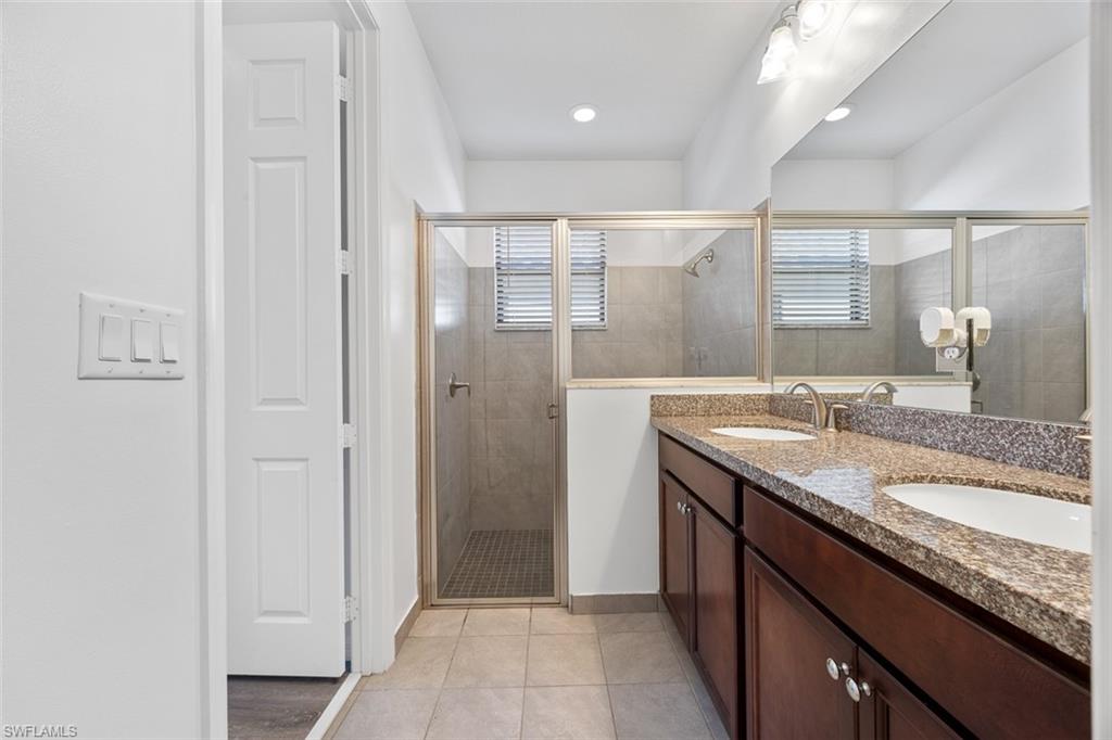 5538 Useppa Drive Ave Maria, FL 34142 - Photo 24 of 35 a bathroom with a granite countertop sink a mirror and a shower