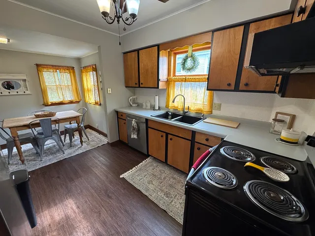 a kitchen with stainless steel appliances granite countertop a stove a sink dishwasher and a microwave with wooden floor