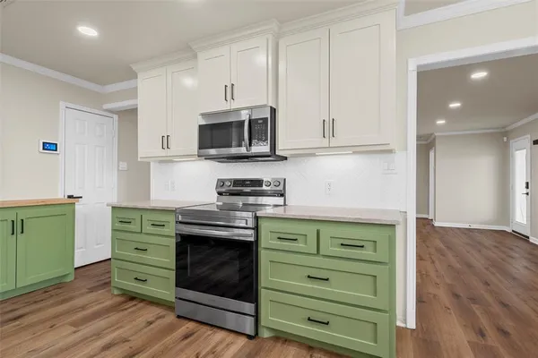 a kitchen with cabinets stainless steel appliances and wooden floor