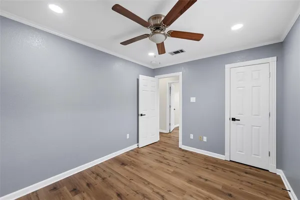 an empty room with wooden floor and ceiling fan